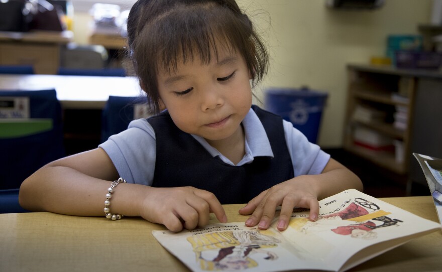 Five-year-old Vivien Huang reads a book in her kindergarten classroom. After being raised in China, her teacher says she's eagerly learning English from picture books.