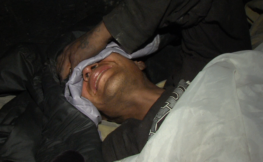 A Tijuana migrant grimaces in pain after he said he was hit by a car running from police, Jan. 15, 2016.