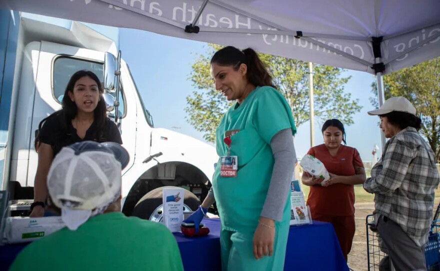 Dr. Navdeep Lehga examines a patient in the parking lot outside the Saint Agnes Mobile Health Unit clinic, located in Rojas Pierce Park in Mendota on Aug. 28, 2025.