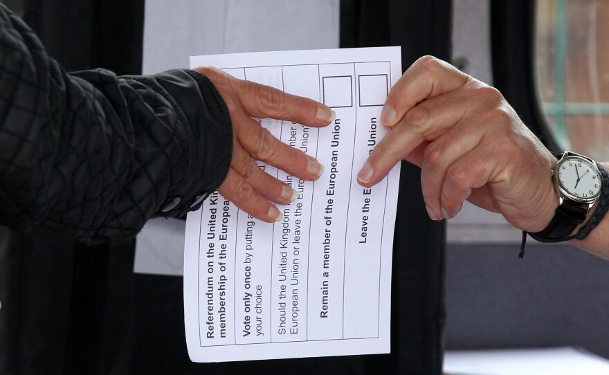 A volunteer hands an unmarked ballot paper to a voter inside a bus being used as a polling station in Kingston-upon-Hull, northern England, on Thursday.