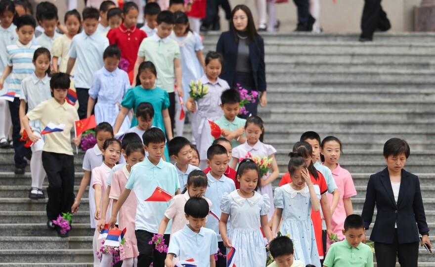 Children holding Russian and Chinese flags walk ahead of a welcoming ceremony for Russian President Vladimir Putin at the Great Hall of the People in Beijing, China Wednesday, May 20, 2026.