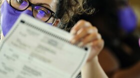 An election worker examines ballots as vote counting in the general election continues at State Farm Arena on Thursday, Nov. 5, 2020, in Atlanta. 