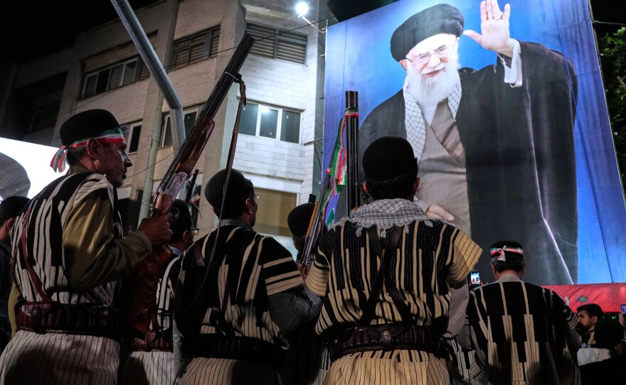 Bakhtiari nomads, wearing traditional dress, hold their guns during a pro-government gathering near the residence where former Iranian Supreme Leader Ayatollah Ali Khamenei, shown on a banner, was killed in U.S. and Israeli strikes on Feb. 28, in Tehran, Iran, Monday, May 18, 2026.