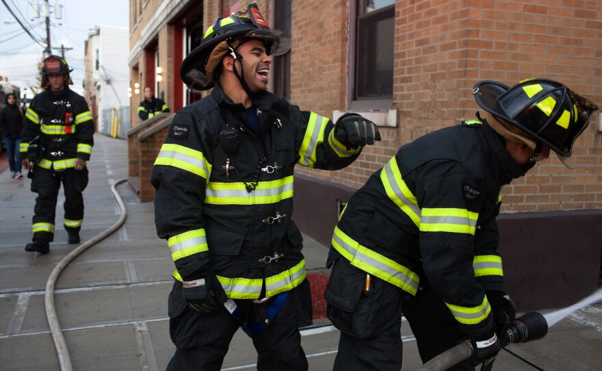 Probationary firefighters Victor Ramos (center) and Andres Godoy (right) joke during training at the 16th Street Firehouse.