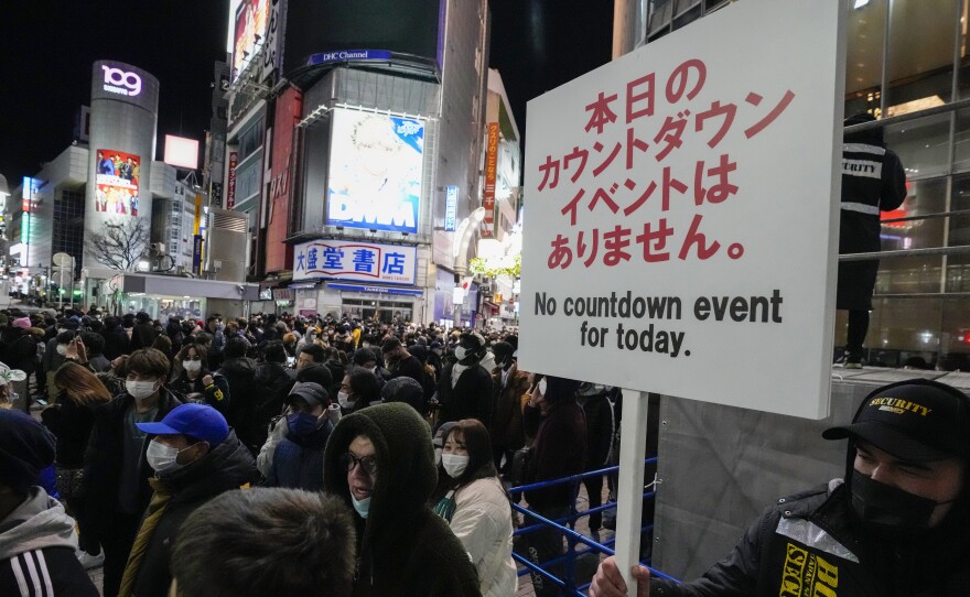 A security guard holds up a sign indicating that there is no countdown event at the famed Shibuya scramble crossing, a popular location for New Year's Eve gathering in Tokyo as people gather to celebrate New Year's eve.
