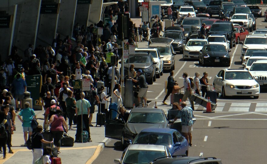 Travelers are shown in the passenger pickup area at San Diego International Airport on September 2, 2022.