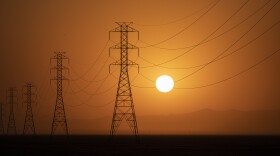 The sun sets behind a row of transmission towers as temperatures rose to a scorching 114 degrees in Fresno County on Sept. 6, 2022.
