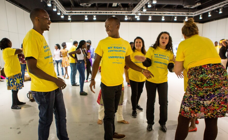 It's flash mob time at the Women Deliver conference: With the help of female delegates, Patrick Segawa of Uganda, center, and Steven Twinomugisha, left, stage a skit about a guy who couldn't find condoms.