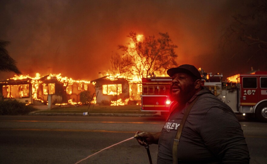 Un vecino arroja agua a su propiedad con una manguera de jardín mientras el incendio Eaton arrasa las estructuras situadas al otro lado de la calle, el miércoles 8 de enero de 2025 en Altadena, California. (AP foto/Ethan Swope, archivo)