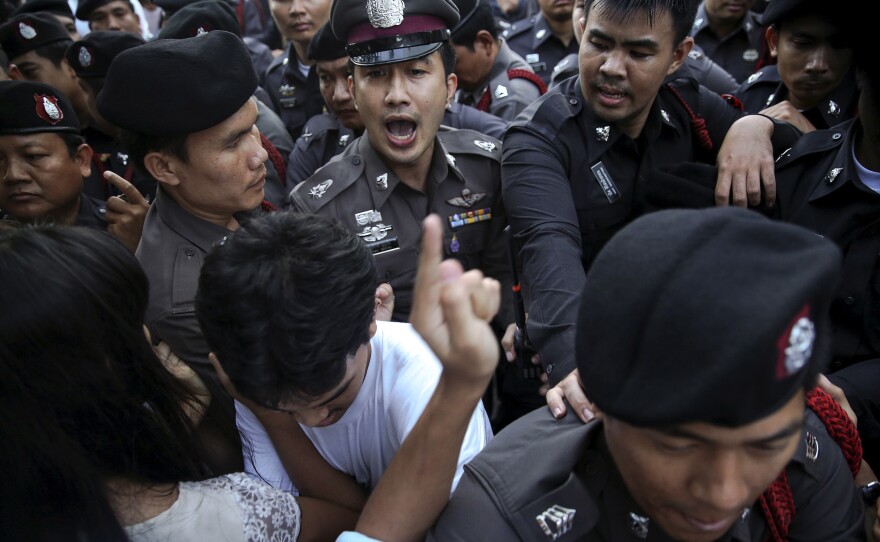 Policemen face protesters during a protest in central Bangkok today. Thai authorities detained dozens of activists protesting against military rule on the one-year anniversary of a coup against the elected government.
