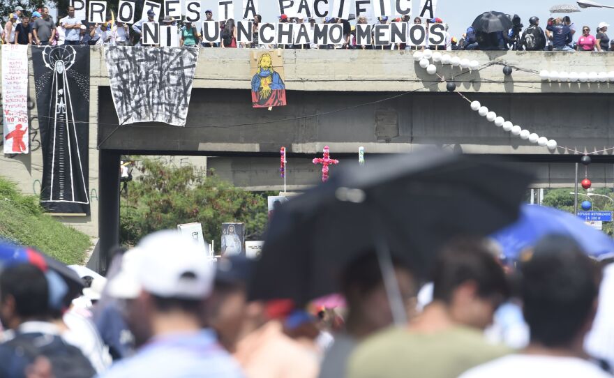 Protesters display signs from an overpass Monday in Caracas as they call for Maduro's ouster. The president blames the unrest — and the economic troubles that helped inspire it — on foreign powers like the U.S.