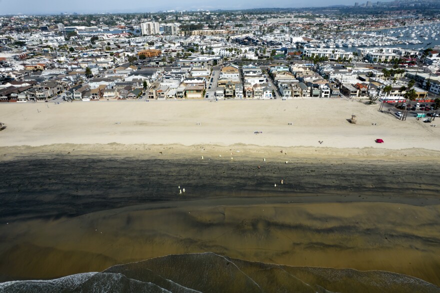 Workers in protective suits clean the contaminated beach after an oil spill in Newport Beach, Calif., on Wednesday, Oct. 6, 2021.