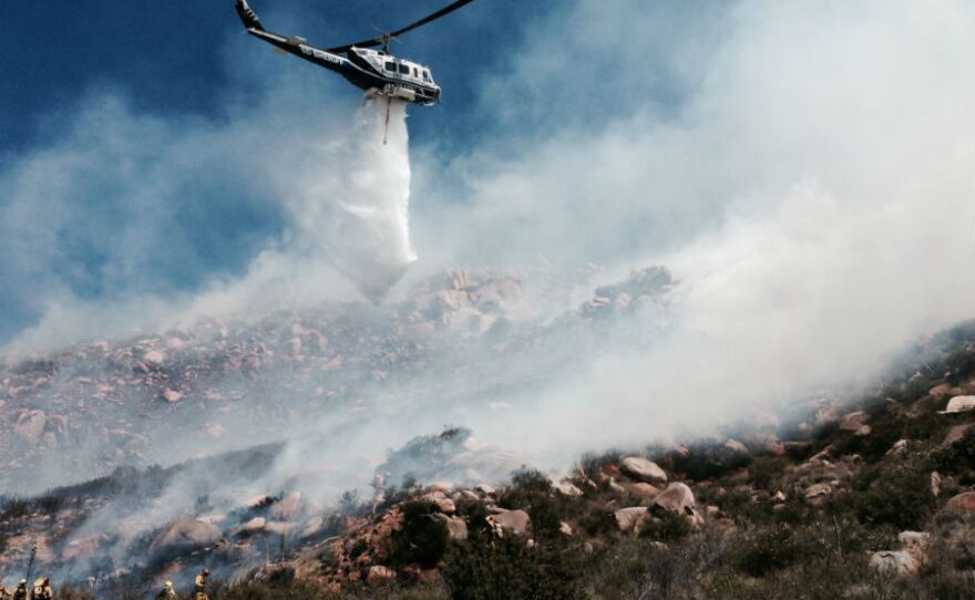 Firefighters use helicopter water drops to put out a brush fire near Alpine on May 3, 2014.