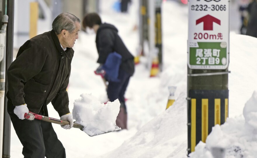 Residents shovel snow off a sidewalk in Kanazawa, Ishikawa prefecture, central Japan, on Dec. 24, 2022.