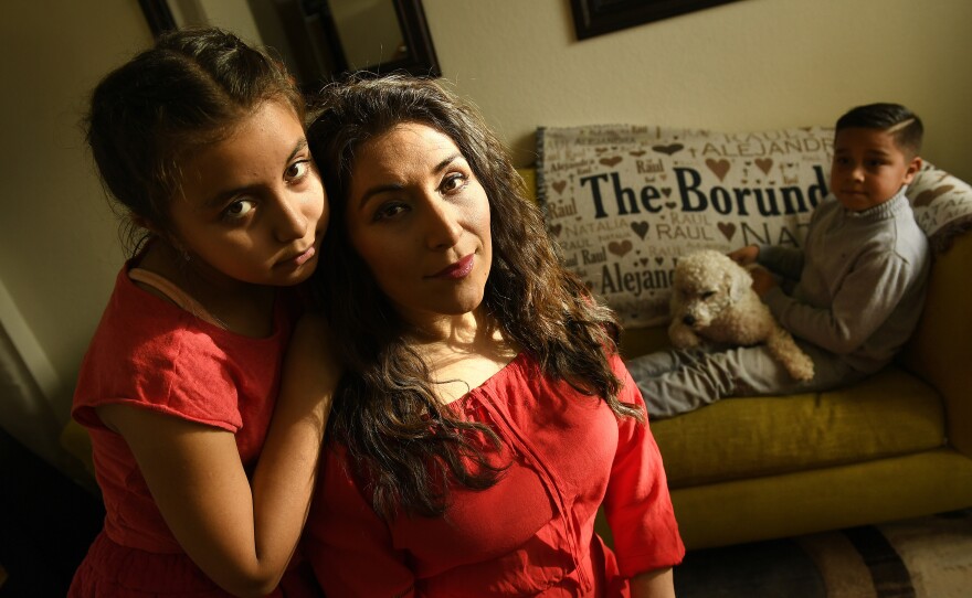 Alejandra Borunda, sits with her two children, Natalia, 11, and Raul, 8, holding the family dog at their home in Aurora, Colo. Borunda's children are among those who would lose out if the CHIP program isn't funded.