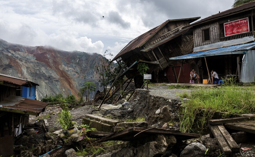 Residents sit near a damaged house caused by a landslide at a mining site in Hpakant in July. The landslide killed nearly 200 people.