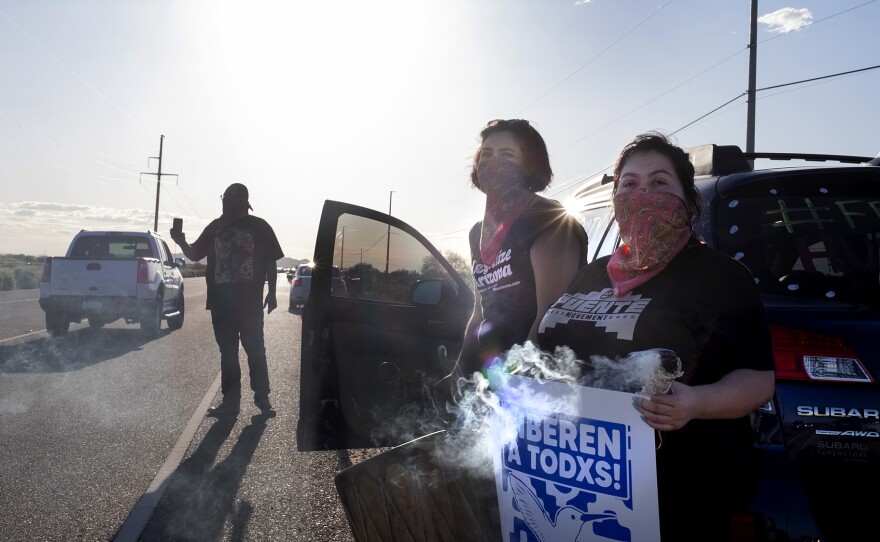 Demonstrators stand along the road in front of the La Palma Correctional Center in Eloy on April 10, 2020. The event was one of several car rallies calling for the release of immigrants detained at the ICE facility during COVID-19.