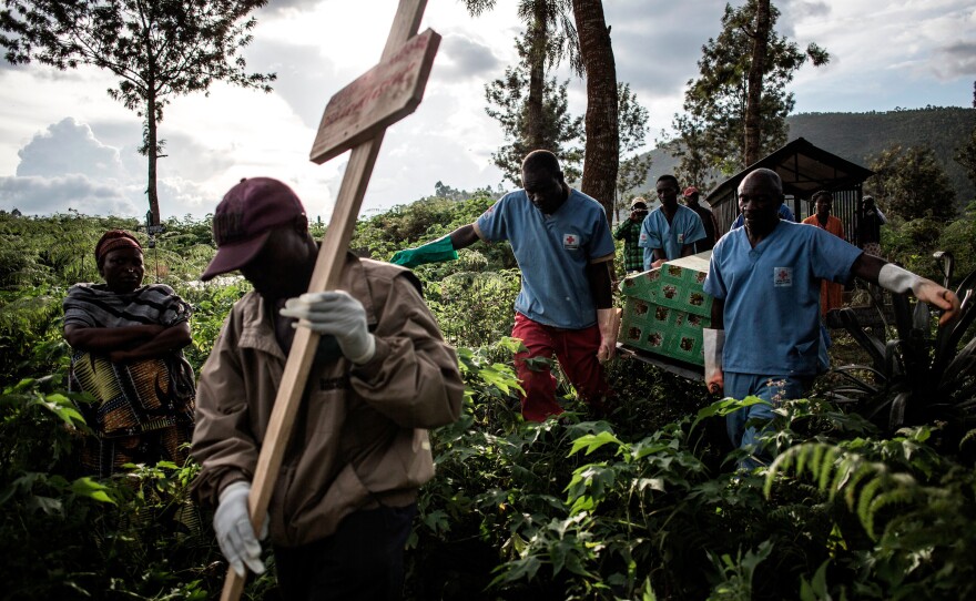Health workers carry the coffins to the burial site.