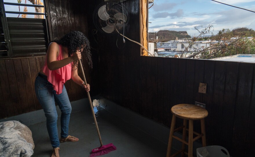 Liz Vazquez Ojeda sweeps water from a rain shower on the floor. The roof was destroyed during the hurricane.