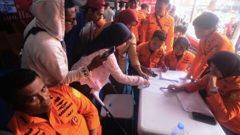 People look for the names of their family members on a passenger list after a ferry overturned in bad weather in the Java Sea, at the rescuers command center in Banjarmasin, South Kalimantan, Indonesia, Sunday, Sept. 13, 2026.