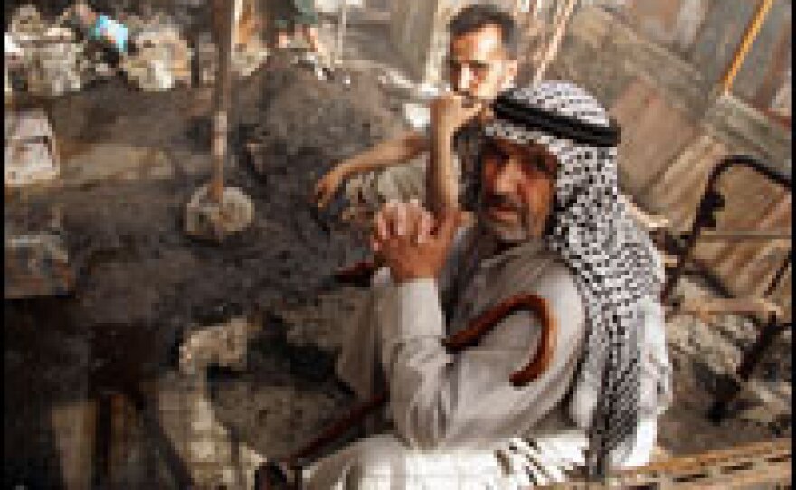 Iraqis sit in a market burned during fighting between Shiite militiamen and Iraqi security forces in Sadr City.