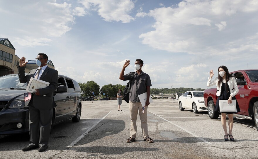 (Left to right) Maweya Babekir, Mulugeta Turuneh and June Yoon Kranci take the U.S. oath of allegiance during a drive-through naturalization ceremony on June 26 at Principal Park in Des Moines.