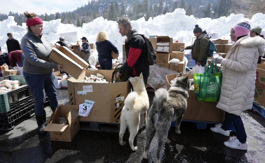 Food is distributed out of a parking lot after a series of storms, Wednesday, March 8, 2023, in Crestline, Calif. 