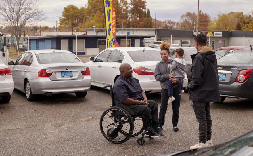 Shehee speaks with his daughter, Sierra Connolly-Shehee, grandson Ezron Alvarez-Connolly and son D'Andre Connolly-Shehee outside the office of the used car lot managed by daughter Shayla Connolly-Shehee in Kennewick, Wash.