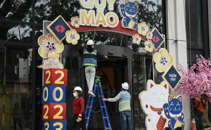 People work on a display of cat figures at a building entrance in Hanoi on Monday.