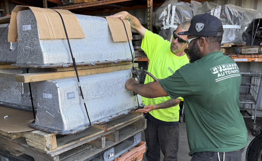 Chris McQuiggen and Archie Brewton of Everett Auto Parts strap two Chevy Volt batteries to a pallet in preparation for shipping. The batteries are separated by a layer of wood so they don't make contact with each other. Everett Auto Parts found a battery recycler who will accept these hybrid vehicle batteries, but the salvage yard won't make any money off of them.