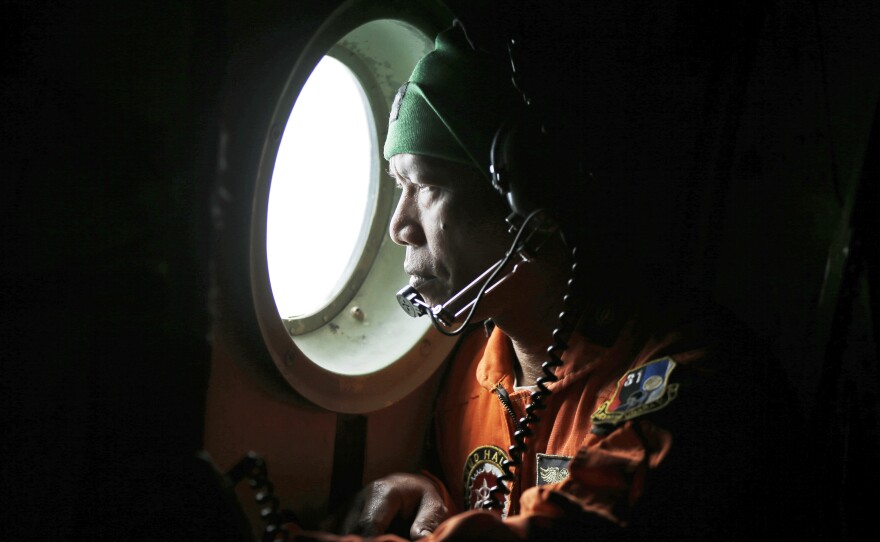 A crew of an Indonesian Air Force C-130 airplane of the 31st Air Squadron looks out of the window during a search operation for the missing AirAsia flight 8501 jetliner over the waters of Karimata Strait in Indonesia, on Monday.