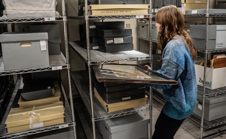 Lisowski moves some of the historical artifacts in a storage room.