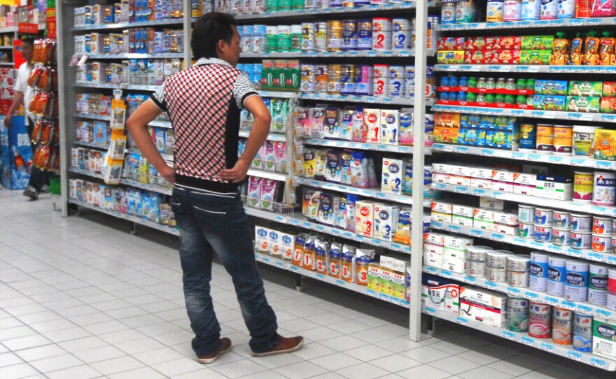 A man shops for milk powder at a supermarket in Guangzhou, south Guangdong Province, on Aug. 12. In 2008, melamine in Chinese milk powder caused the deaths of at least six children and made nearly 300,000 children ill. Now some Chinese say they're choosing foods more carefully.