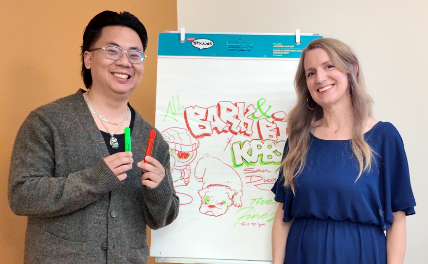 Sign painter and content creator Koy Sun, left, and The Finest host Julia Dixon Evans pose with a drawing Koy created while waiting backstage before KPBS Podcasts Live: The Art of Protest on July 12, 2026.