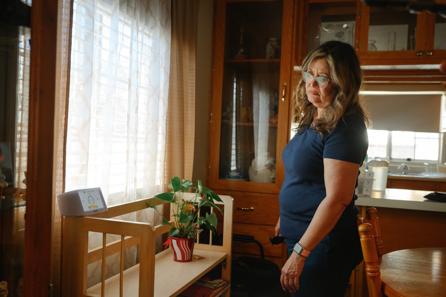 Maggie Morales checks the air quality on a monitor at her mother Margarita Garcia’s home in the Old Town neighborhood of National City, California on June 27, 2025.