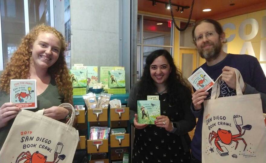 Organizers and booksellers are pictured with totes and swag during the 2019 San Diego Book Crawl in an Apr. 27, 2019 photo in San Diego, Calif. Pin designer Susie Ghahremani is at center, and Library Shop manager Scott Ehrig-Burgess is at right.