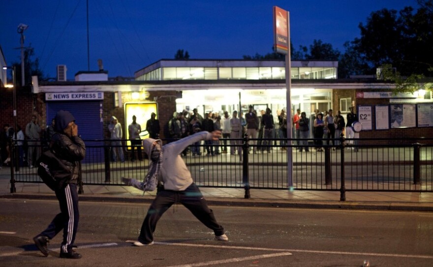 Youths throw bricks at police in this Sunday, Aug. 7, 2011 photo  during unrest in Enfield, north London. Nearly 1,200 people have been arrested since the riots erupted Saturday, mostly poor youths from a broad section of Britain's many races and ethnicities.  Britain is bitterly divided on the reasons behind the riots.