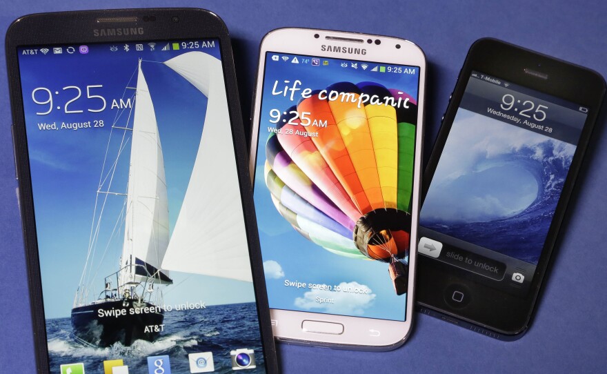 The Samsung Galaxy Mega (from left), Samsung Galaxy S4, center and Apple iPhone 5 are shown. Apple is expected to announce larger models of its smartphone on Tuesday.