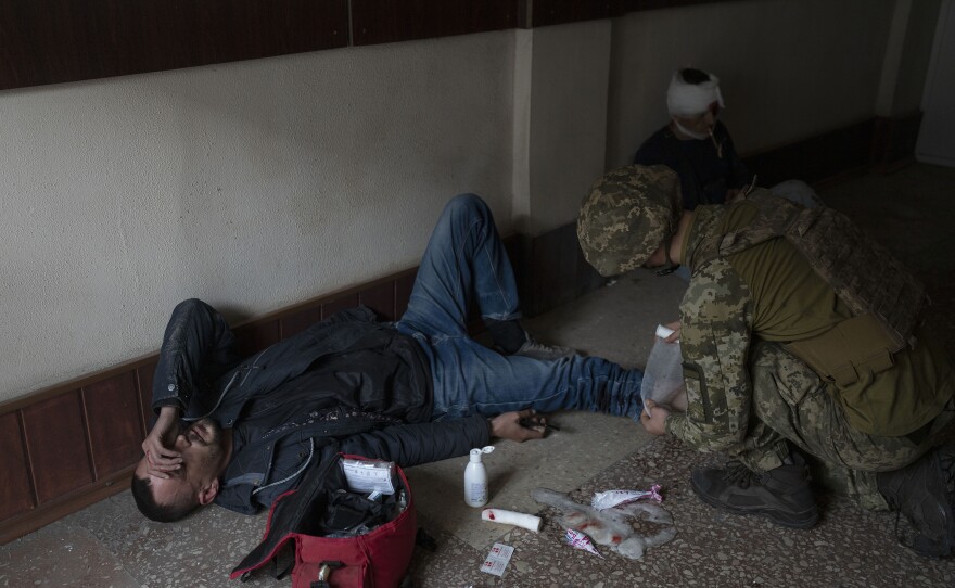 <strong>April 19:</strong> A member of Ukraine's security forces administers first aid to an injured man following Russian bombing of a factory in Kramatorsk, in eastern Ukraine, that killed at least one person and injured three others.