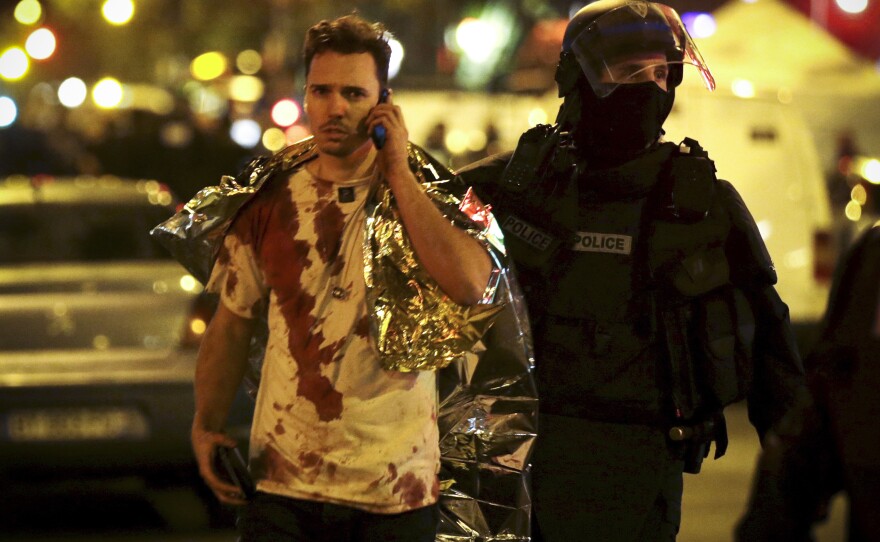 A French policeman assists a victim near the Bataclan concert hall.