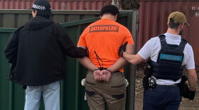 In this photo provided by the Australian Federal Police, a man, center, is arrested by police in Londonderry in western Sydney, Friday, June 19, 2026.