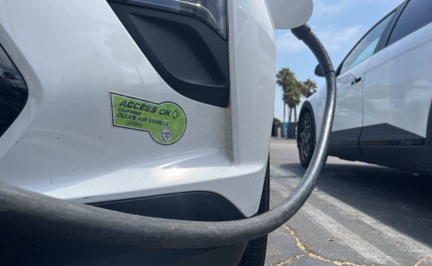 An electric vehicle with a Clean Air Vehicle decal charges at a public lot in Encinitas, Aug. 12, 2025.