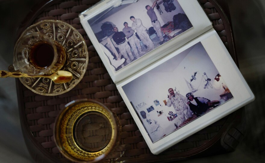 A photo album of Shihab — during his time as an interpreter working with American military personnel during the Iraq War — rests on a small table alongside cups of tea.