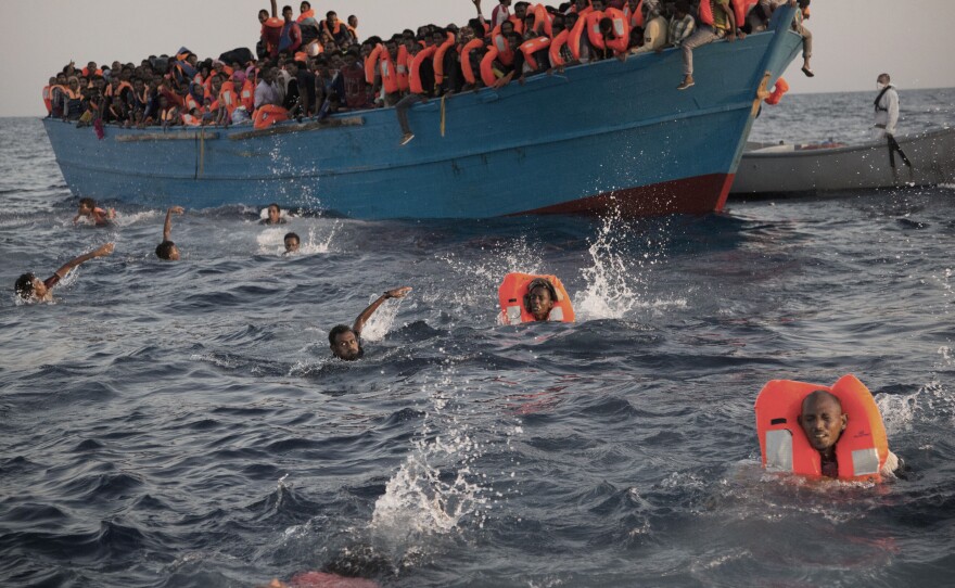 People, most of them from Eritrea, jump from a crowded wooden boat to swim toward a rescue ship about 13 miles north of Sabratha, Libya, on Monday.