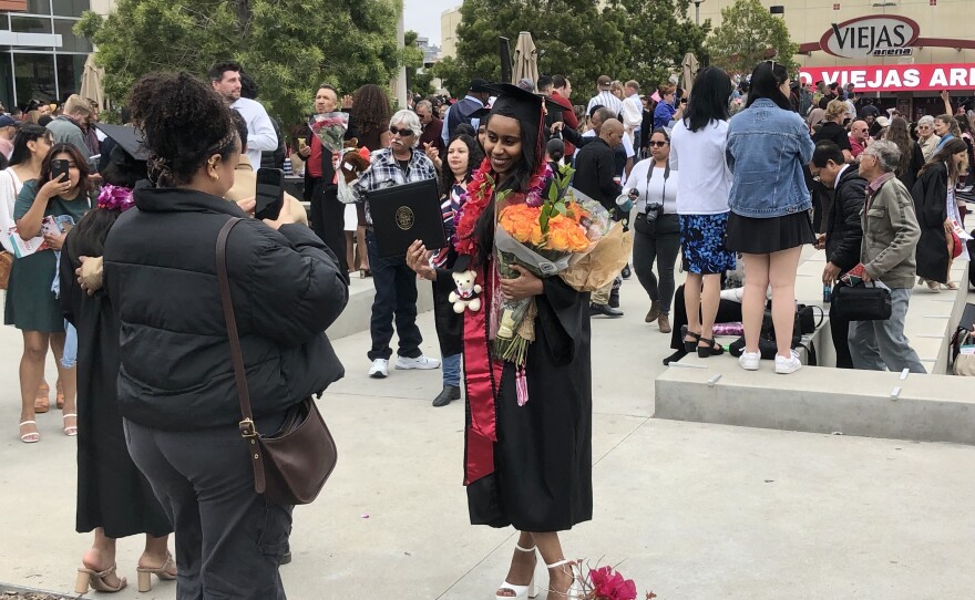 A new graduate is shown having her picture taken in front of Viejas Arena at San Diego State on May 12, 2023.