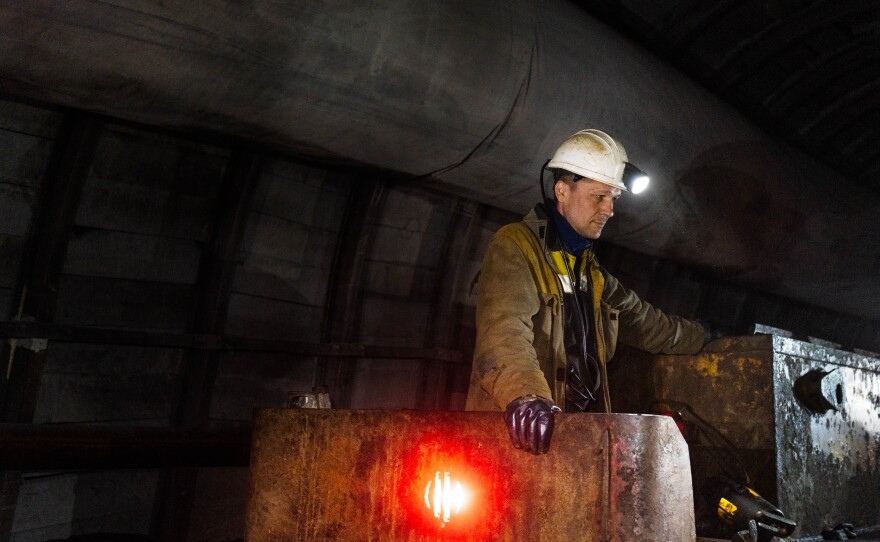 An operator of the mine railway that carries people in and out of the depths of the mine waits as workers disembark.