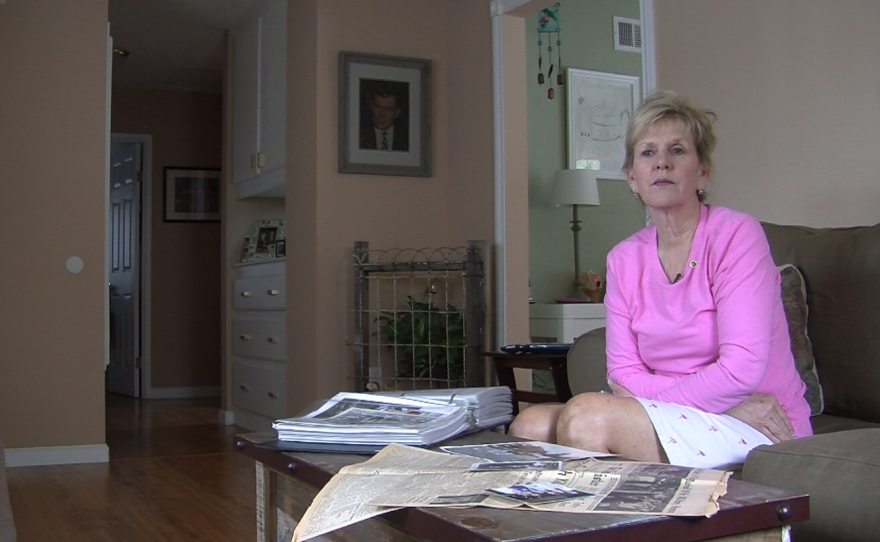 Patty Lee stares out her living room window after displaying photos and articles of her father, an Army master sergeant killed in Vietnam in 1967. A portrait of her dad, Delbert C. Totty, and part of a fence she helped him create are shown in the corner behind her.