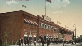 A policeman on horseback stands outside Fenway Park; colored photograph.