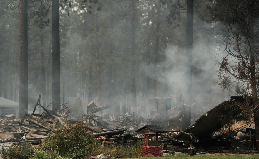 A burned structure smolders due to a wildfire, on Aug. 2, 2026, in Spokane, Wash.