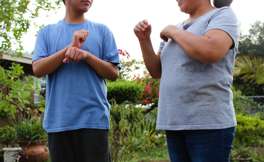 A Guatemalan teen asylum-seeker (left), who isn't able to hear or speak, signs with his mom in Florida. He was brusquely separated from her and held in a shelter for nearly three months, unable to readily communicate, according to a civil rights complaint filed with the Department of Homeland Security.
